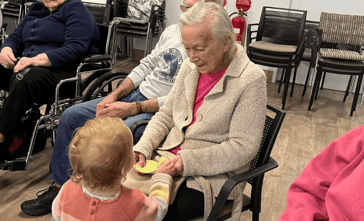 A child from AnglicareSA's childcare service engaging with an elderly lady at an aged care home. 