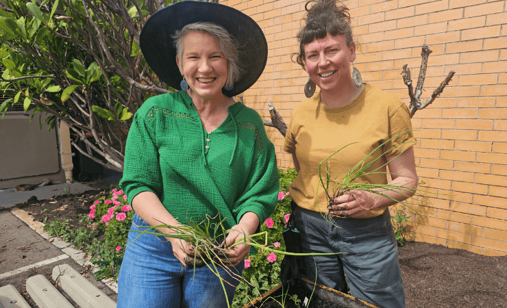Two people doing gardening outdoors with plants in their hands.
