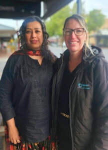 2 smiling woman standing in front of road