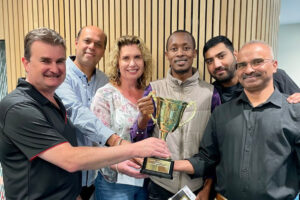 A photo of Grant, AnglicareSA CEO, Emmanuel and his team holding a trophy.