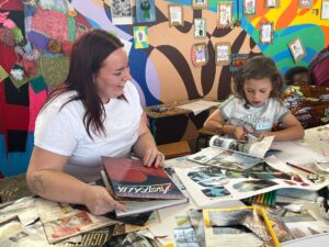 Young woman sitting with child looking in art magazines