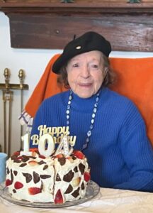 Woman smiling sitting in front of 104th birthday cake