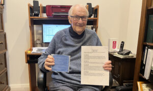 An older man holding a script in one hand and a CD in other hand