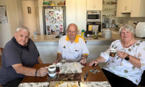2 older men and 1 woman sitting at a coffee table holding coffee mugs