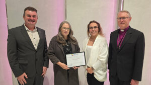 A group of four well dressed people standing holding an award