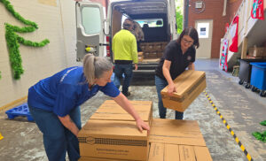 2 women unloading boxes of Kyton's pudding for Anglicaresa's christmas hamper and toy drive