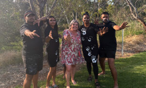 Woman in pink floral dress standing in the middle of first nations dance group