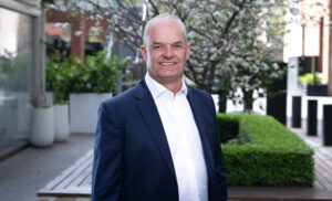 Man in suit stands outside in a courtyard area