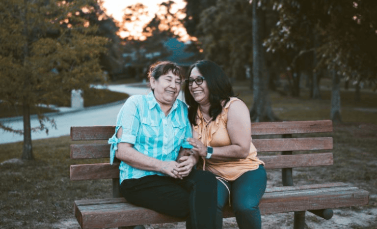 Two ladies seated on a bench laughing