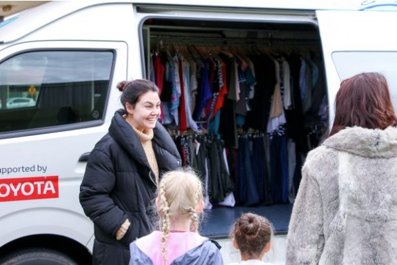 A lady handing out clothes from a van