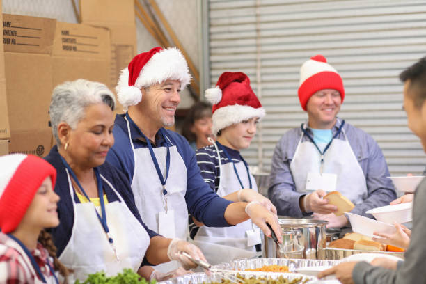 Multi-ethnic, mixed age group of volunteers serves food at a soup kitchen. A variety of food is being served to the under-resourced people in their local community. Christmas season.