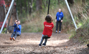 child in red shirt seated on flying fox
