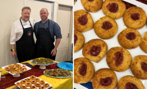 two chefs standing together in front of table with snacks upon it
