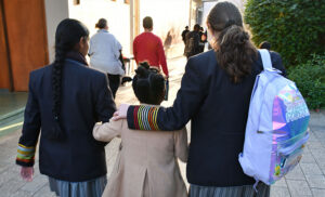 3 school kids walking outside, shot from the back