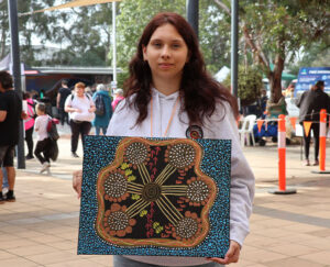 Young girl holding aboriginal australian inspired artwork