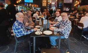 a group of older men sitting at a table together at a pub