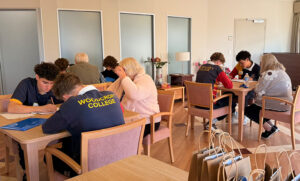 a room full of aged care residents sitting with students engaging in conversation