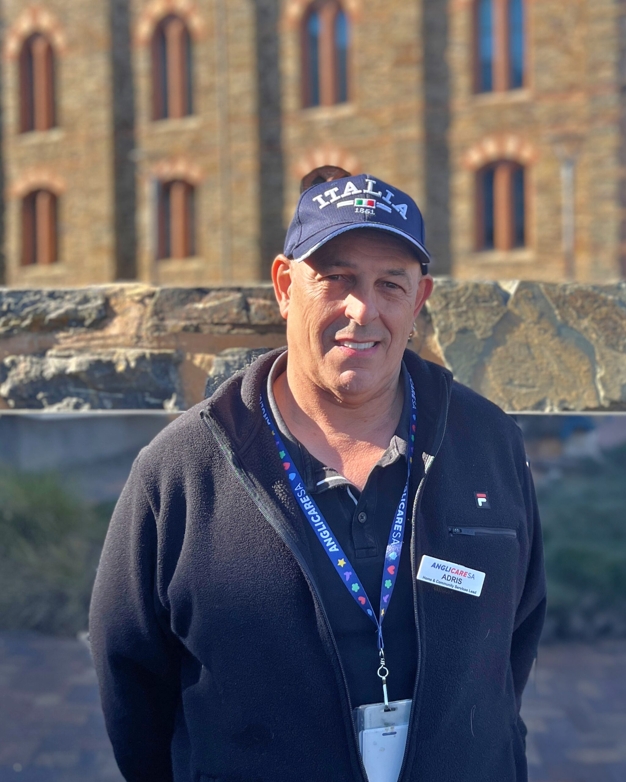 AnglicareSA Employee, Adris, stands in front of an old building.