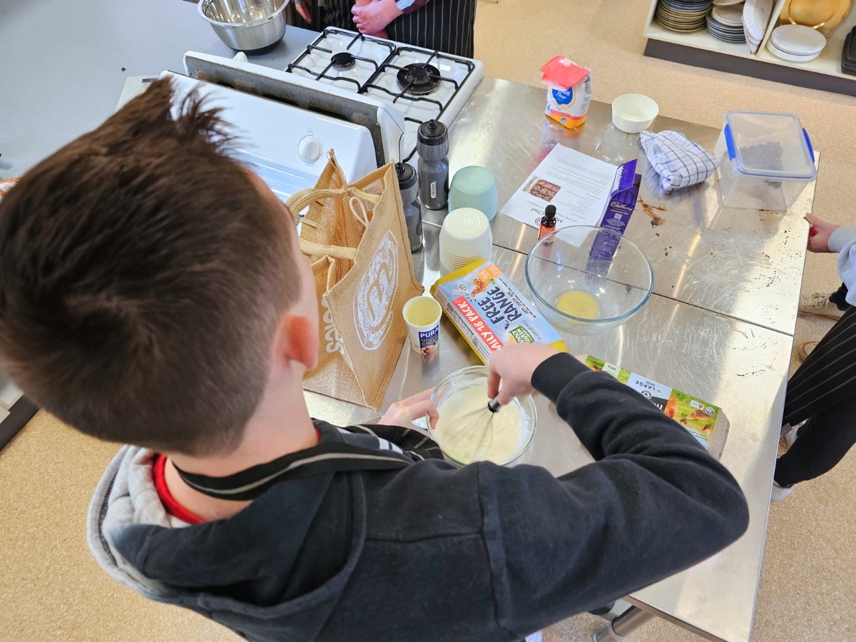 A young person is cooking brownies, mixing ingredients in a bowl. 