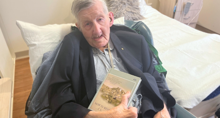 Ken Clezy in his room at Elizabeth East Residential Care holding his book.