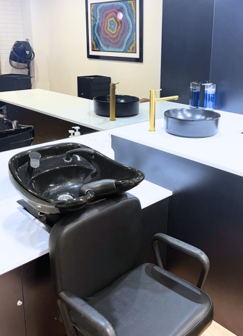 The new hair salon has black leather chairs, black wash basin with white bench tops and gold tapware.