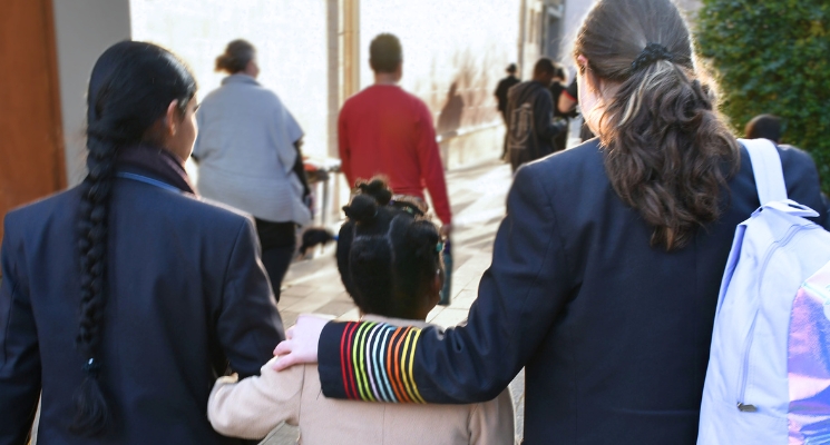 Two Wilderness School students walk with their arm around a small child.