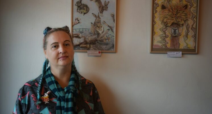 Artist Bianca Bampton stands in front of her framed drawings.