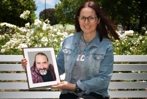 Jo sits on a white bench holding a photo of her husband Davide.