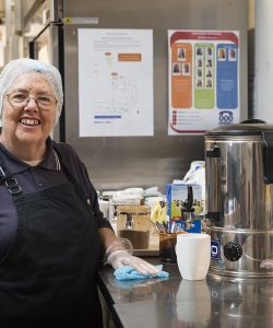Lady smiling in a kitchen cleaning and making a hot drink