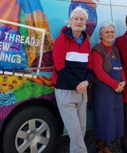 two men and two women smiling and standing in front of a van