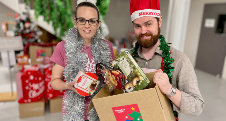 AnglicareSA staff Astra and Ben are dressed up in festive costumes with tinsel and Christmas hats.