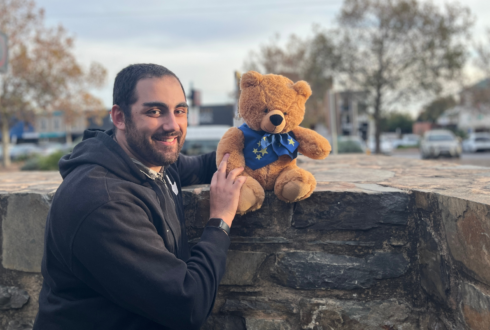 Sebastien stands smiling with one of the Star Bears teddy bears