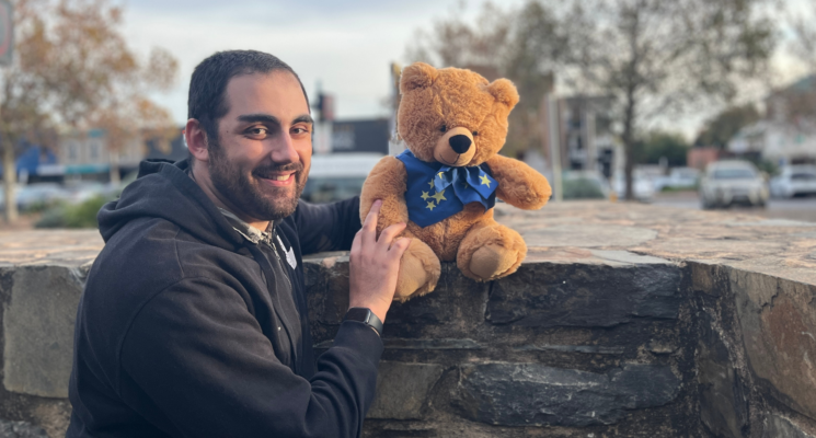 Sebastien stands smiling with one of the Star Bears teddy bears