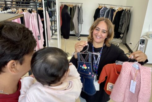 Volunteer Samah stands holding children's clothing.